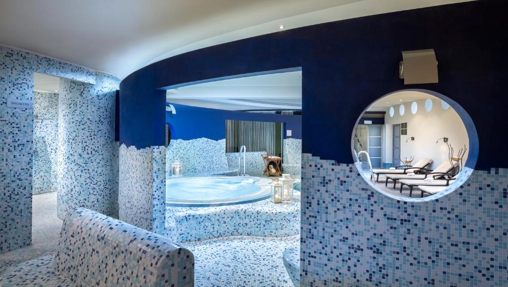 a blue bathroom with a tub and a mirror at Valamar Diamant Hotel in Poreč