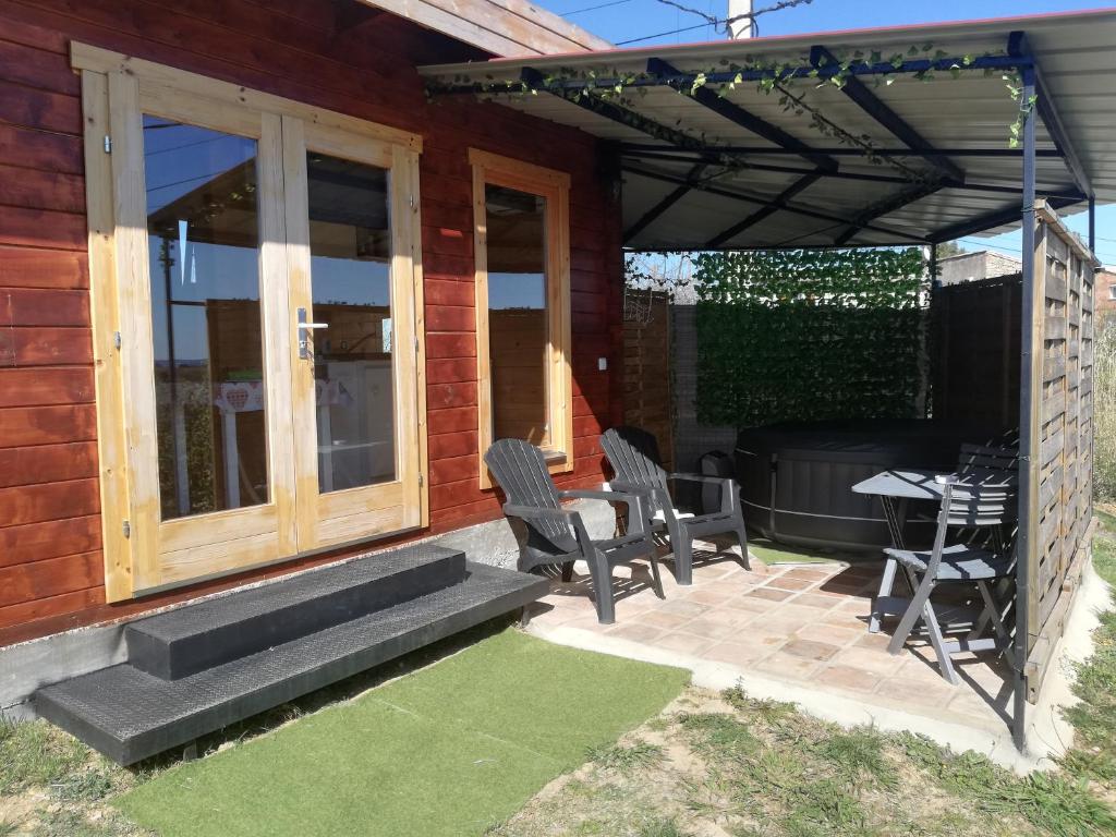 eine Terrasse mit Stühlen, einem Tisch und einem Grill in der Unterkunft Charmant Chalet pour 2 personnes SPA privé in Massillargues-Attuech