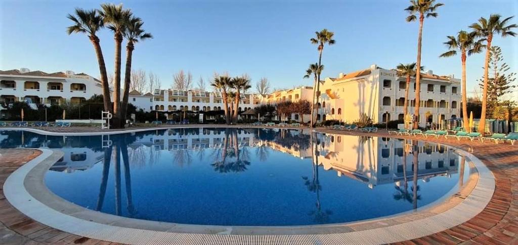 uma grande piscina com palmeiras e edifícios em Casa Marias I - inserido no Resort Golden Club Cabanas em Cabanas de Tavira