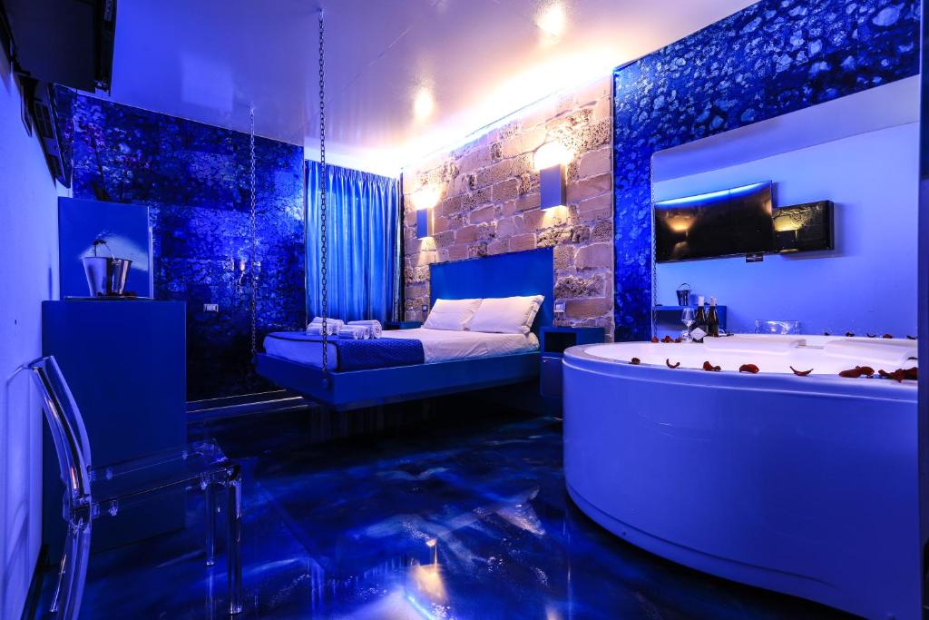 a blue bathroom with a tub and a bed at Villa Asfodelo Guest House & Relax in Alghero