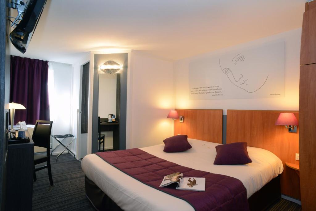 クウェッティニーにあるHotel inn Dijon-Quetignyの大きなベッドとデスクが備わるホテルルームです。