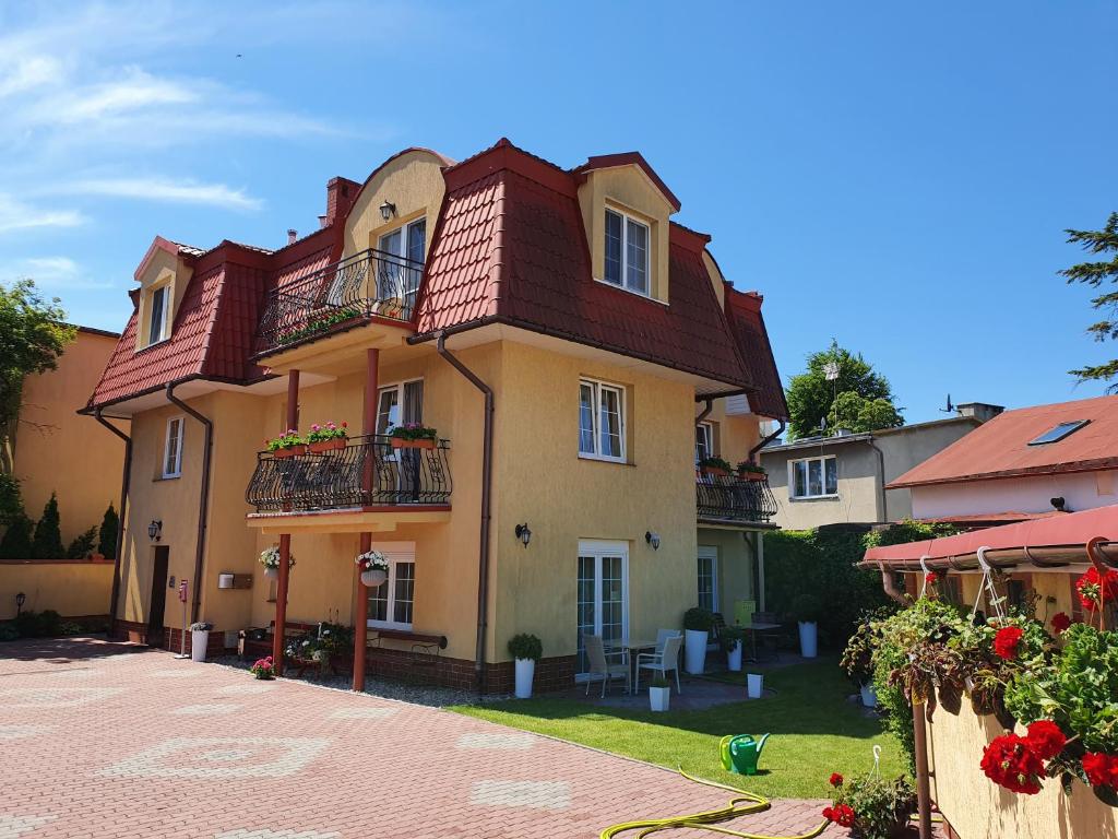 a large building with balconies and flowers in a yard at Amberek Dom Gościnny in Międzyzdroje