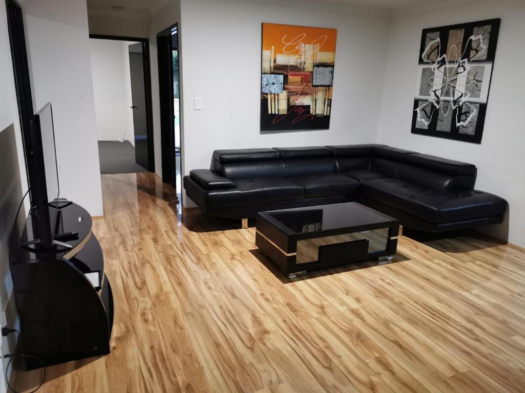 Sala de estar con sofá de cuero negro y mesa de centro en Perth Urban Lodge en Perth