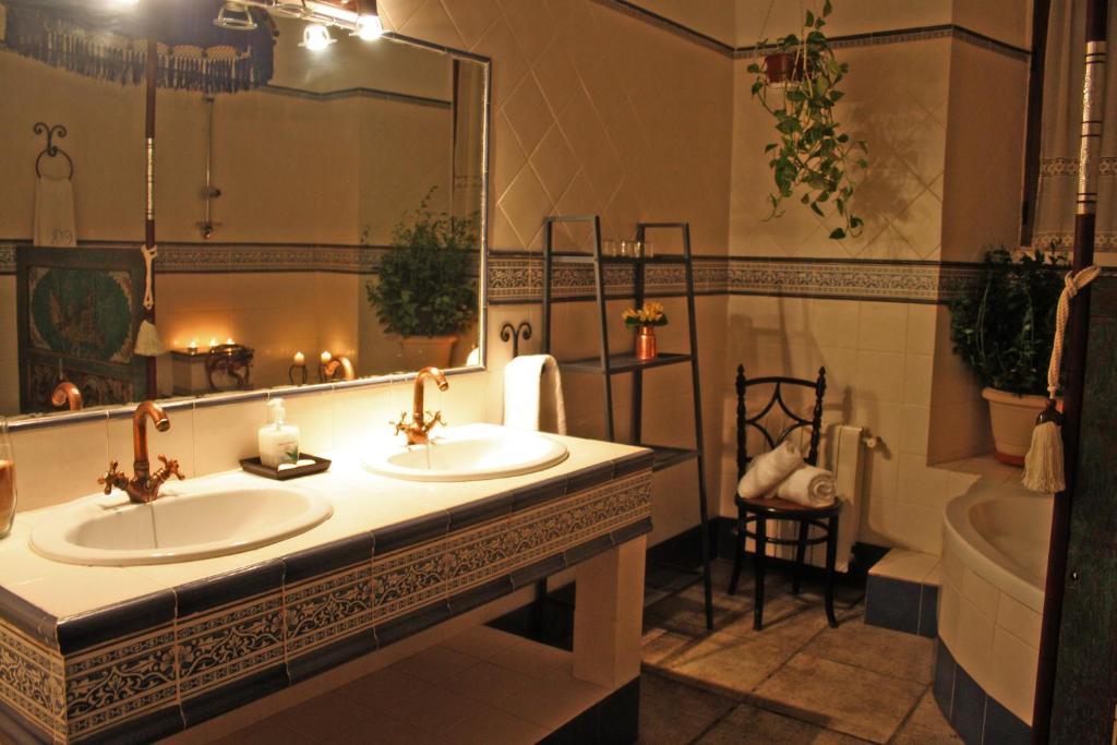 Un baño con dos lavabos y un espejo grande. en Casa Rural El Aguila, en Montemolín
