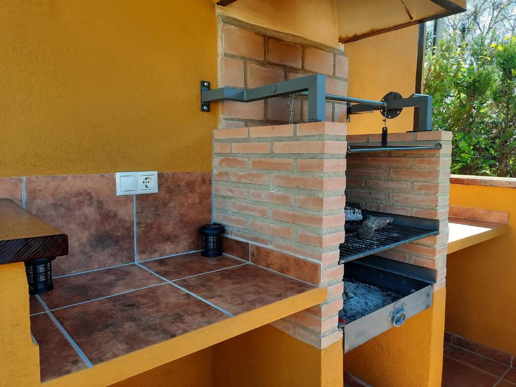 a stone fireplace in a house with a brick wall at EL REFUGIO DE POPEA in Santa María de Trassierra