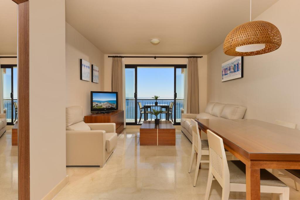 a dining room and living room with a table and chairs at Precioso apartamento de 2 dormitorios con parking & WiFi in Torrox Costa
