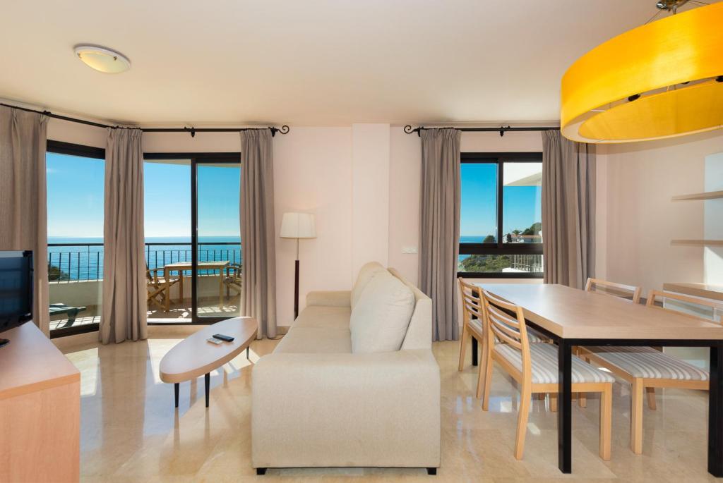 uma sala de estar com uma mesa e uma sala de jantar em Fantástico apartamento de 1 dormitorio frente al mar em Torrox Costa