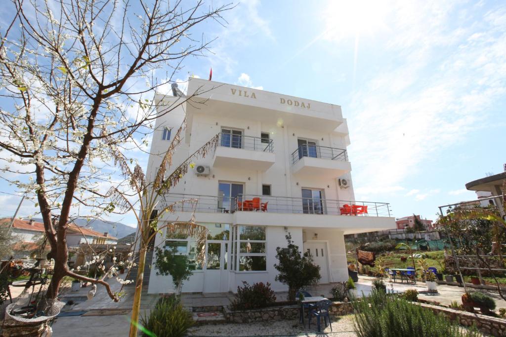 un bâtiment blanc avec des chaises rouges devant lui dans l'établissement Vila Dodaj, à Ksamil