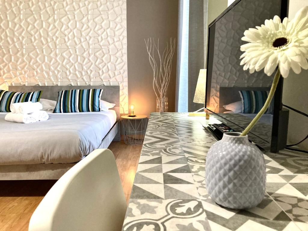 Un dormitorio con una cama y un jarrón con una flor en B&B Stesicoro InHabit - GuestHouse City Center, en Catania
