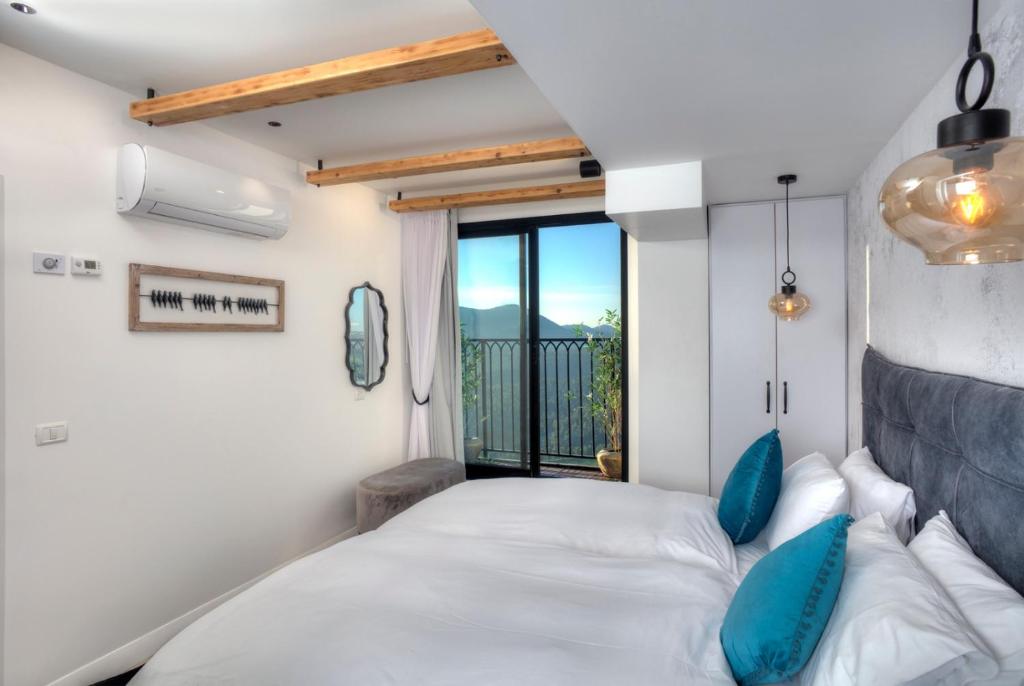a bedroom with a bed with blue pillows and a window at Open Skys in Safed