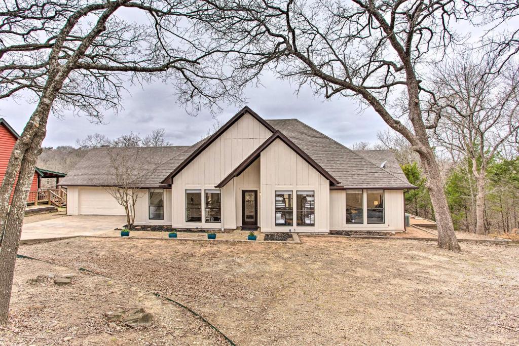 une grande maison blanche avec un arbre dans la cour dans l'établissement Lake Texoma Retreat with Deck Less Than 1 Mi to Marina!, à Pottsboro