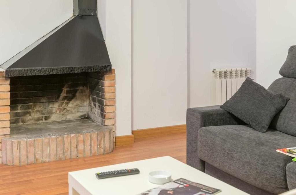 sala de estar con sofá y chimenea en Candelario apartamentos, en Candelario