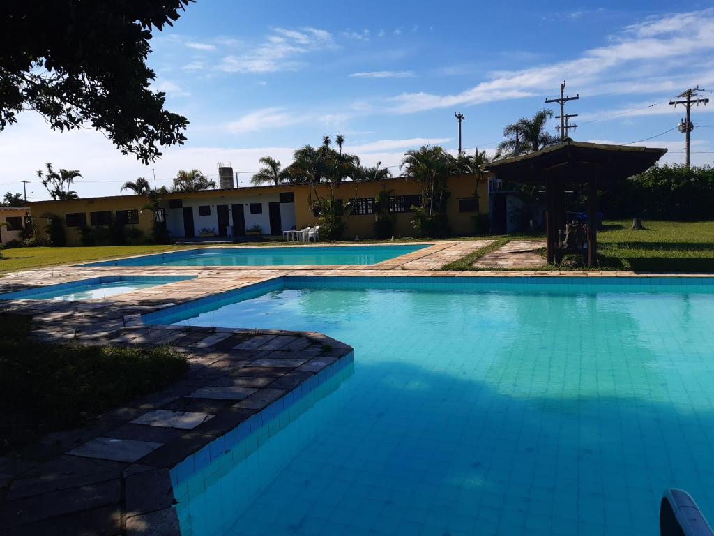 uma grande piscina azul com um edifício ao fundo em Samburá Chalés em Ilha Comprida