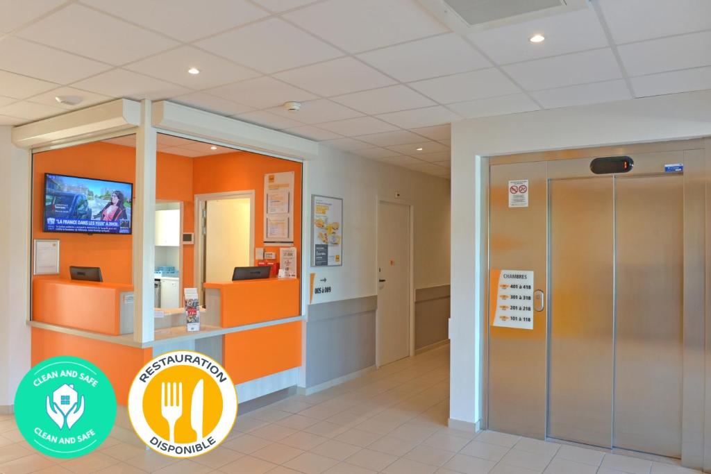 an office lobby with an orange wall and an elevator at Premiere Classe Reims Nord - Bétheny in Bétheny