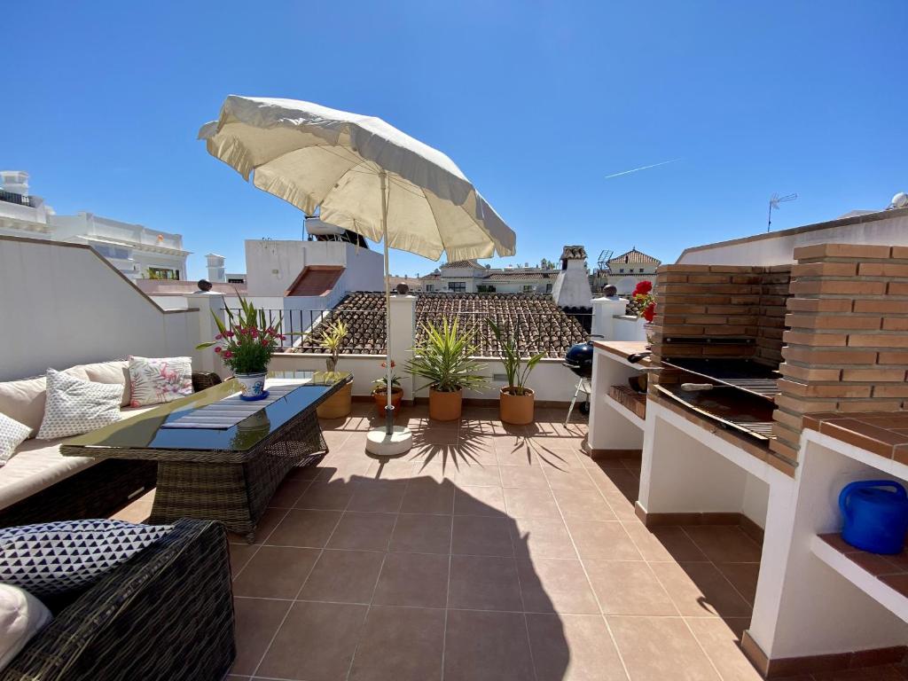 a rooftop patio with a table and chairs and an umbrella at Casa Animas Casasol Centro in Nerja