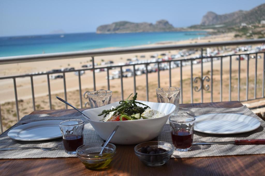 a bowl of salad on a table with a view of the beach at Panorama Hotel in Falasarna