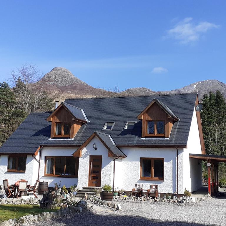 a large white house with mountains in the background at Beechwood Cottage B&B in Glencoe