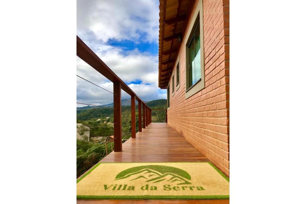a wooden walkway leading to a building with a welcome mat at Villa da Serra Ibitipoca chalé família in Conceição da Ibitipoca