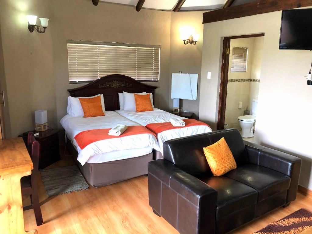 a bedroom with a large bed and a leather couch at Gaggle Inn Guest Lodge in Kroonstad