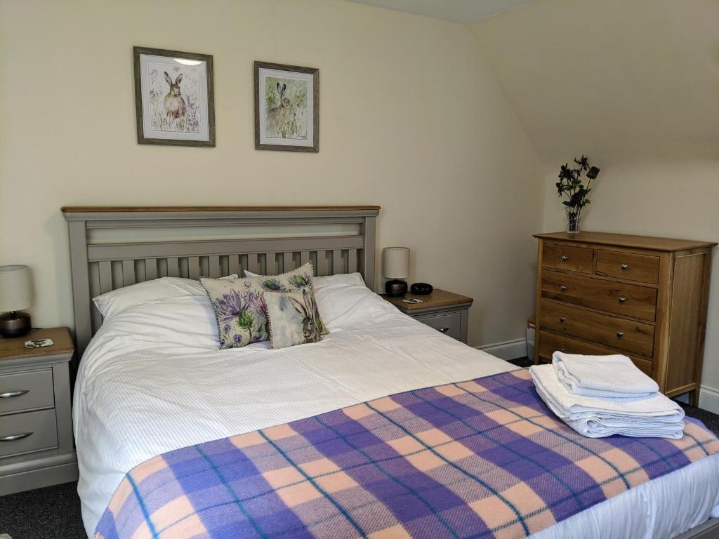 a bedroom with a bed with a plaid blanket at Kinloch Rannoch Holiday Cottage in Kinloch Rannoch