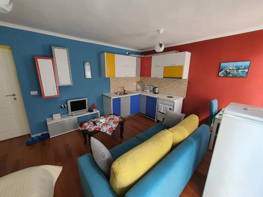 My Apartments Polican في Poliçan: غرفة معيشة مع أريكة زرقاء ومطبخ
