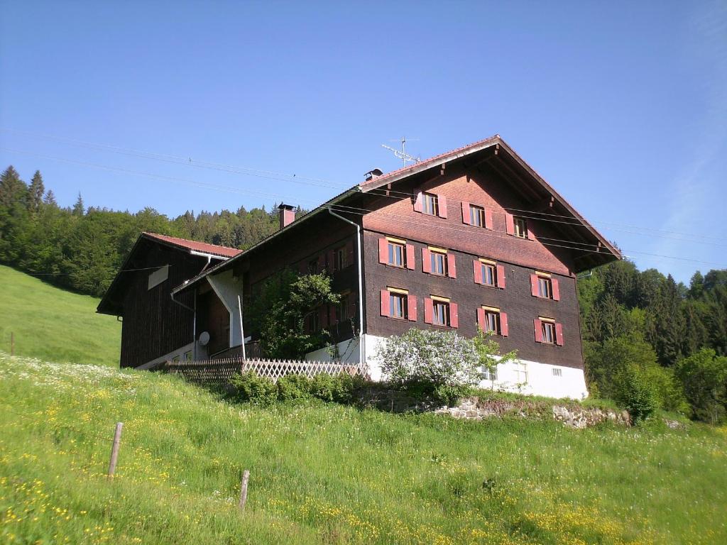 ein großes Gebäude auf einem Hügel auf einem Feld in der Unterkunft Ferienwohnungen Brunner in Fischen im Allgäu