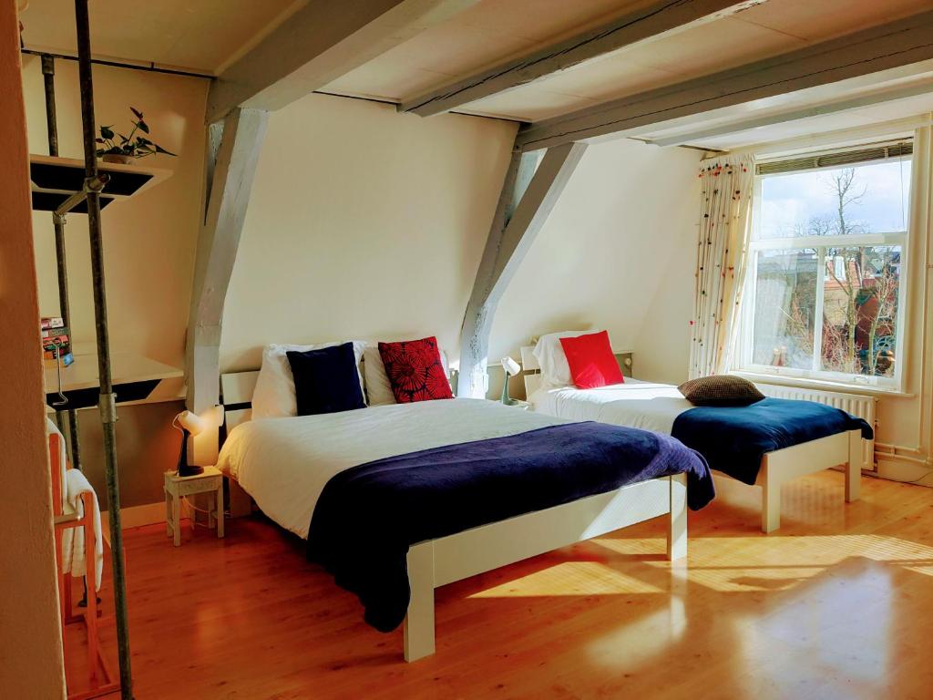 een slaapkamer met twee bedden en een raam bij B&B Hart van Leiden in Leiden