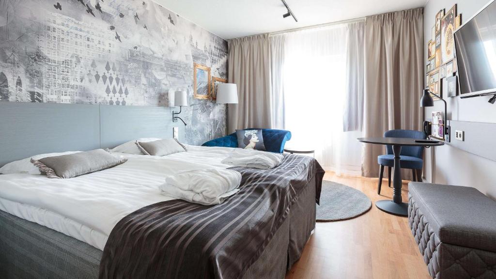 una habitación de hotel con una cama grande y una silla en Scandic Kuopio en Kuopio