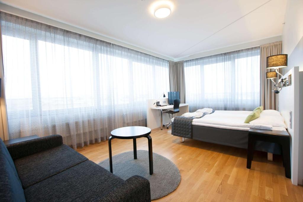 a bedroom with a bed and a couch and a table at Scandic Pori in Pori