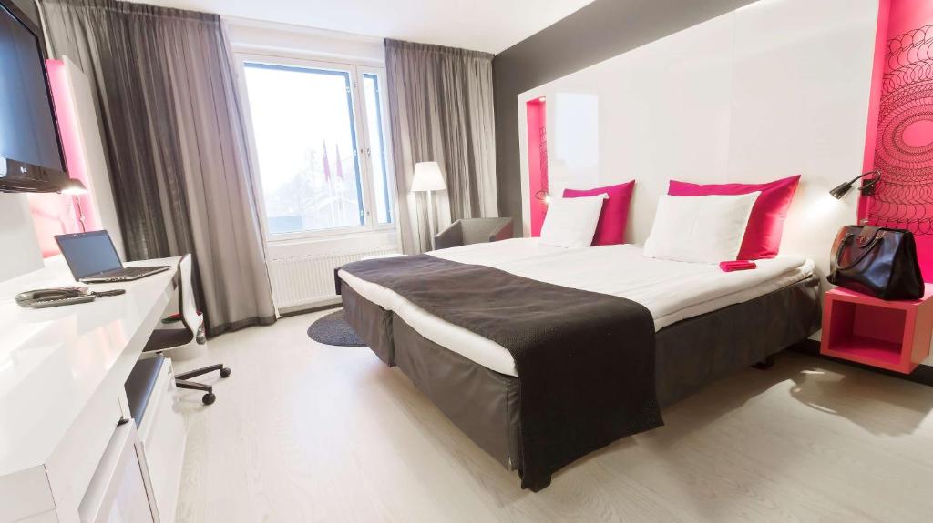 a hotel room with a large bed with red pillows at Scandic Tampere Station in Tampere