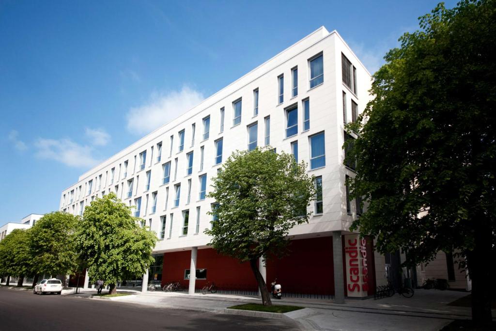 a white building on a street with trees in front at Scandic Kristiansand Bystranda in Kristiansand