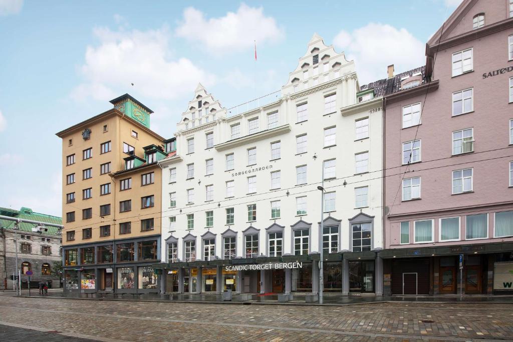 a white building on a street next to other buildings at Scandic Torget Bergen in Bergen