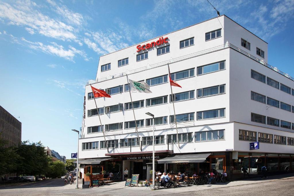 un edificio blanco alto con banderas. en Scandic St. Olavs Plass, en Oslo