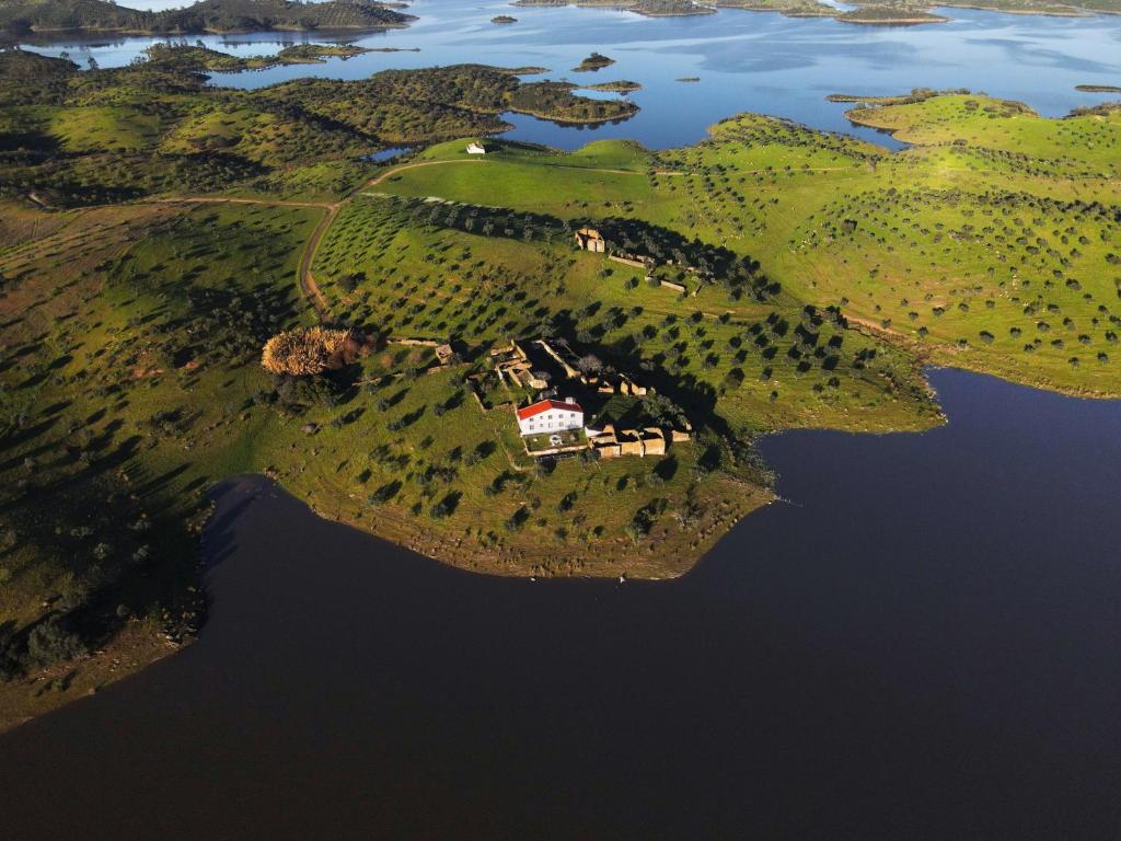 une île dans l'eau avec une maison sur elle dans l'établissement Herdade Monte da Tapada, à Alqueva