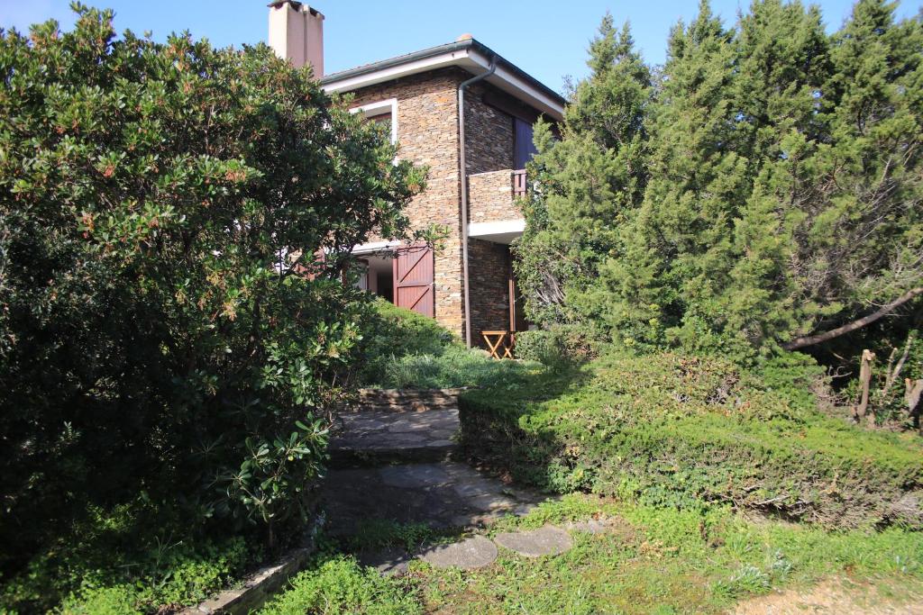 ein Haus inmitten eines Gartens mit Bäumen in der Unterkunft B&B Sa Serra in Stintino