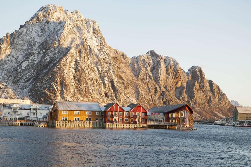 un grupo de casas en el agua con una montaña en Scandic Svolvær en Svolvær