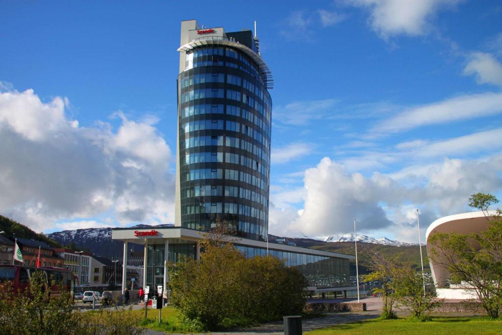 ein hohes Glasgebäude vor einem Gebäude in der Unterkunft Scandic Narvik in Narvik