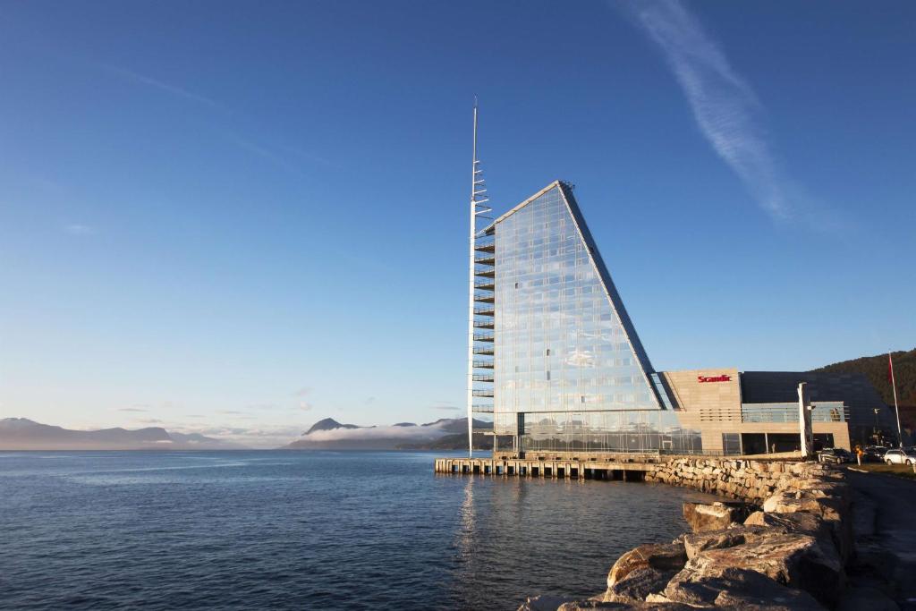 a building on the water next to a body of water at Scandic Seilet Hotel in Molde