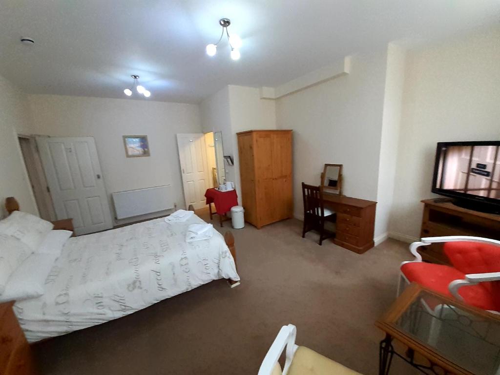 a bedroom with a bed and a desk and a television at The Edenhurst Guesthouse in Weymouth