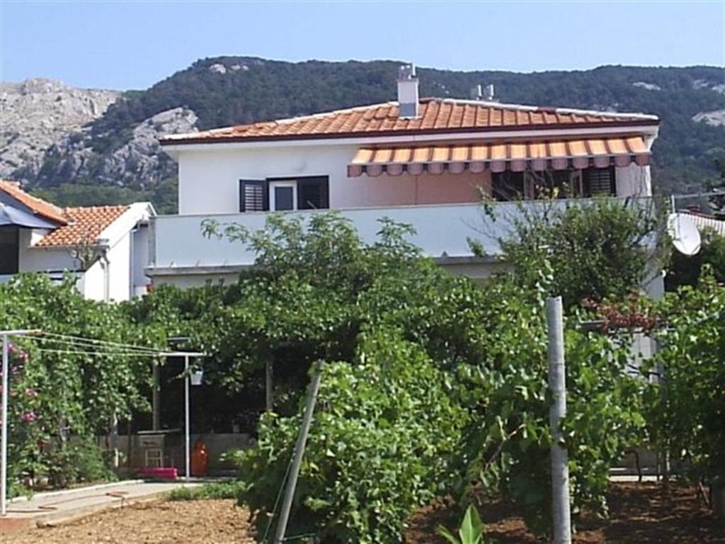 una casa blanca con árboles delante de ella en Apartments Tanja & Boris, en Baška