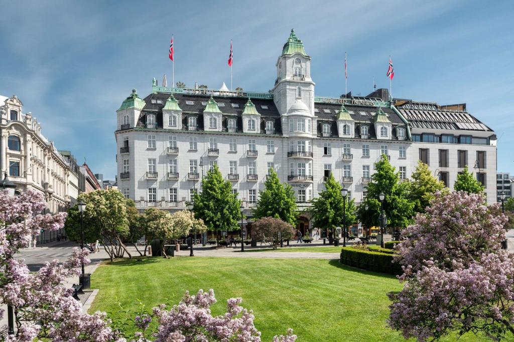 Grand Hotel Oslo في أوسلو: مبنى أبيض كبير مع حديقة أمامه