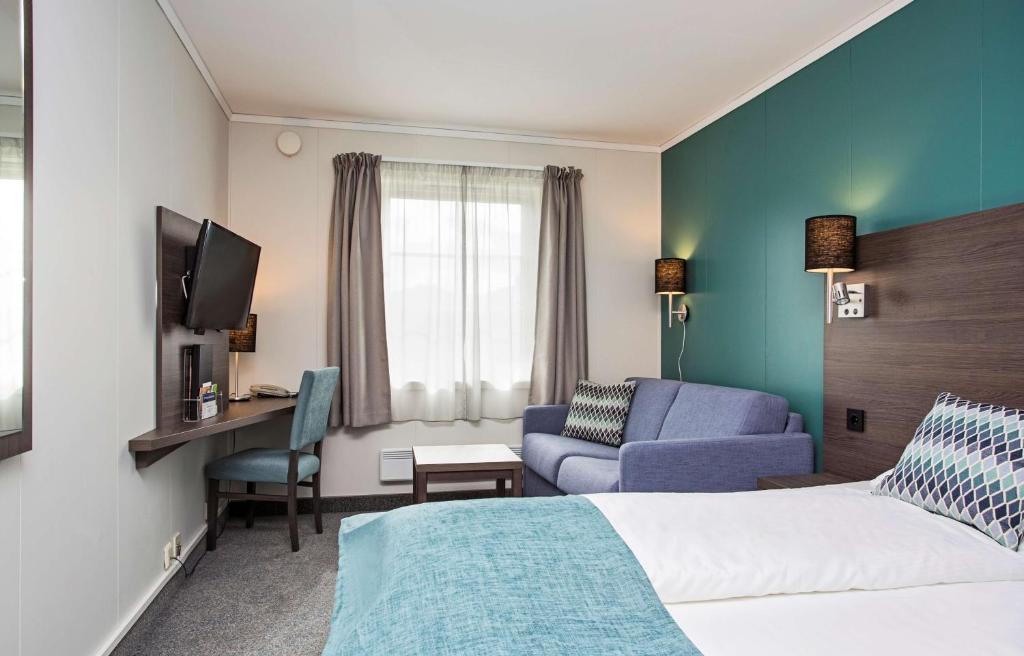 Scandic Leknes Lofoten في ليكنيز: غرفة في الفندق بها سرير وتلفزيون وأريكة