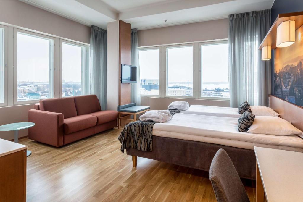 een grote slaapkamer met een groot bed en een bank bij Scandic Meilahti in Helsinki