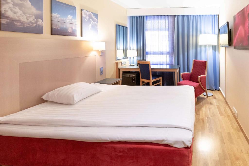 a hotel room with a bed and a desk at Scandic Kouvola in Kouvola