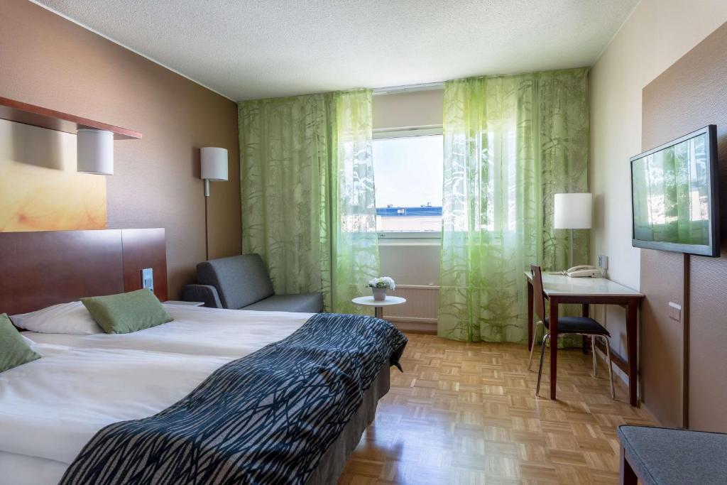ユヴァスキュラにあるスカンディック ユヴァスキュラ シティのベッド、デスク、窓が備わるホテルルームです。