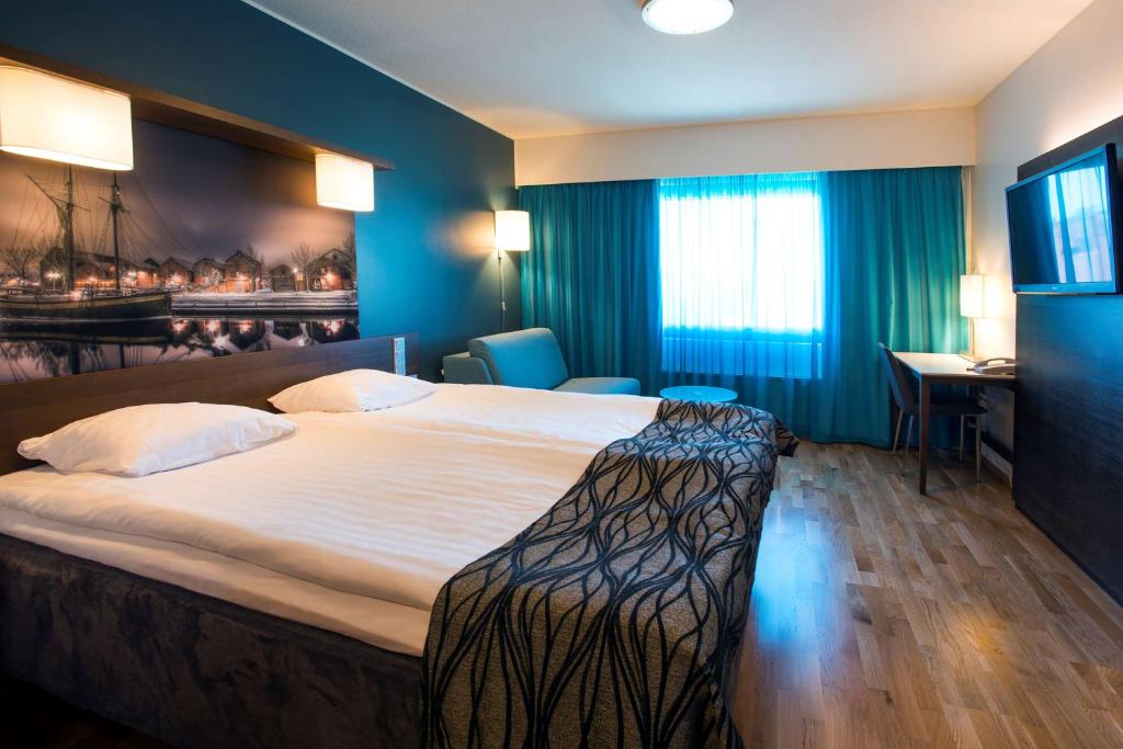 a hotel room with a large bed and a desk at Scandic Oulu Station in Oulu