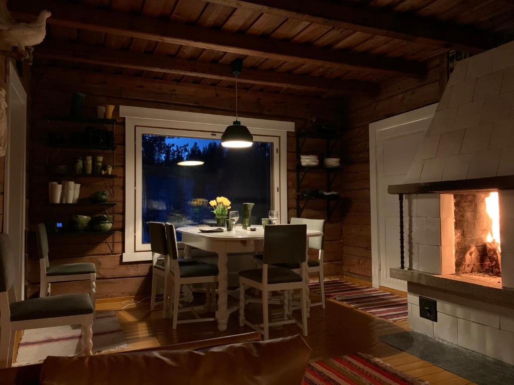 a dining room with a table and a fireplace at Saariselällä, sielukas hirsimökki - Unique cottage in Saariselka