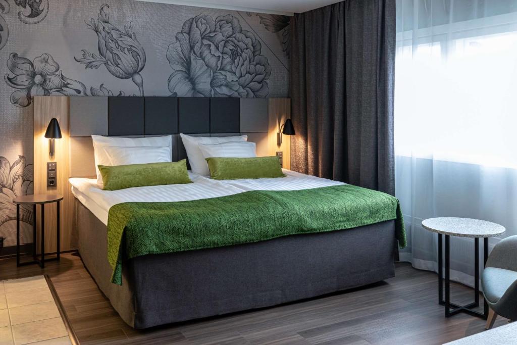 a bedroom with a large bed with a green blanket at Scandic Pasila in Helsinki