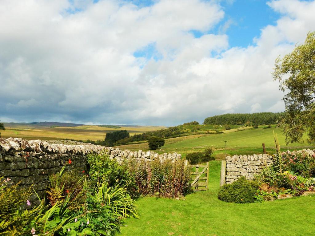 une clôture en pierre dans un jardin avec un mur en pierre dans l'établissement Roman Cottage - - Hadrian's Wall dark sky outpost., à Newcastle upon Tyne