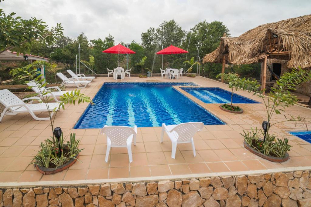 - une piscine avec des chaises et des parasols blancs dans l'établissement Cabana Costa Azul, à Coveñas